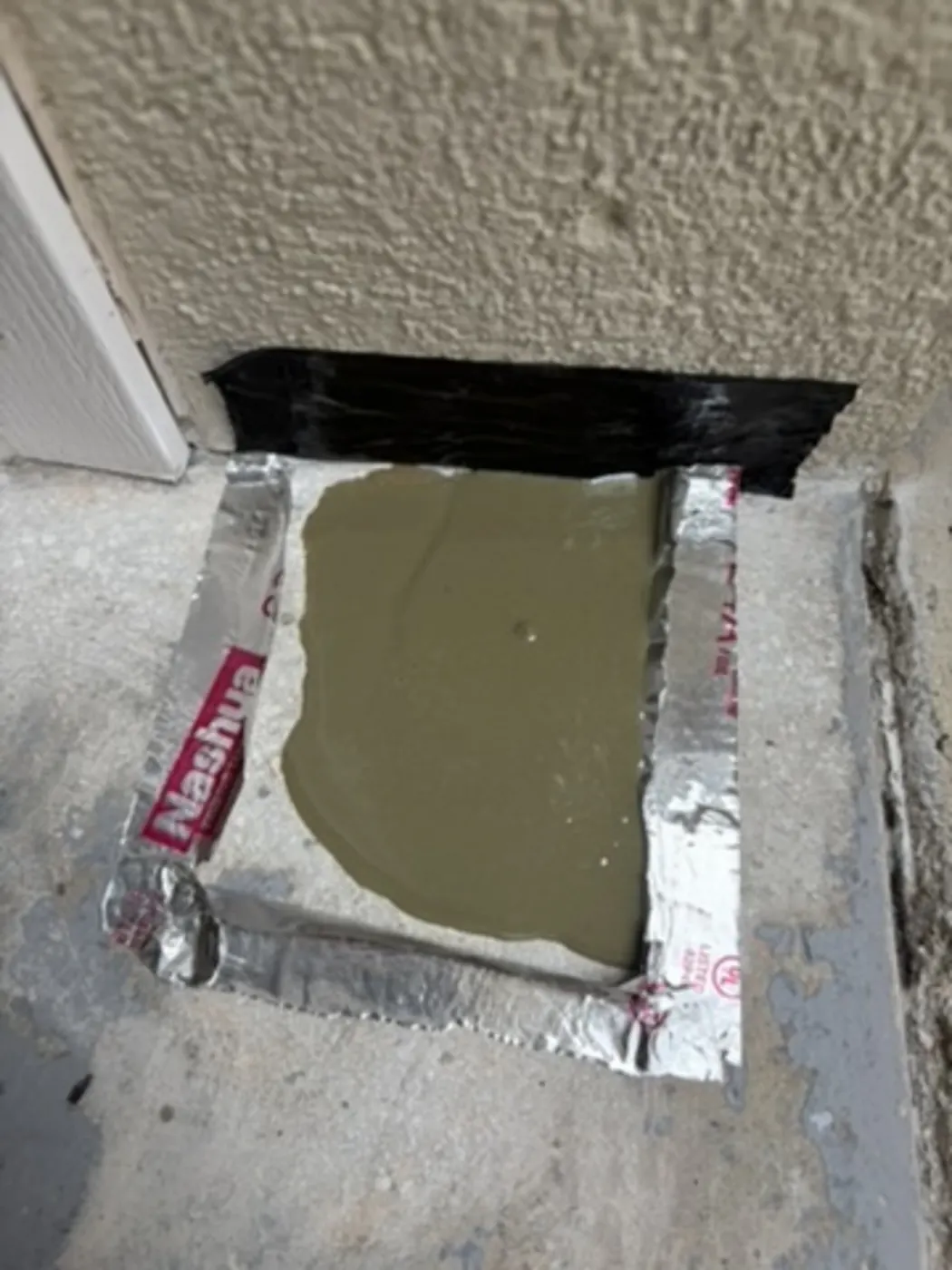 Concrete patch material taped off to cure before epoxy coating